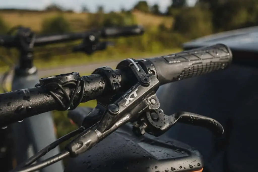 Close up of mountain bike brake lever, Shimano XT, with nature in the background.