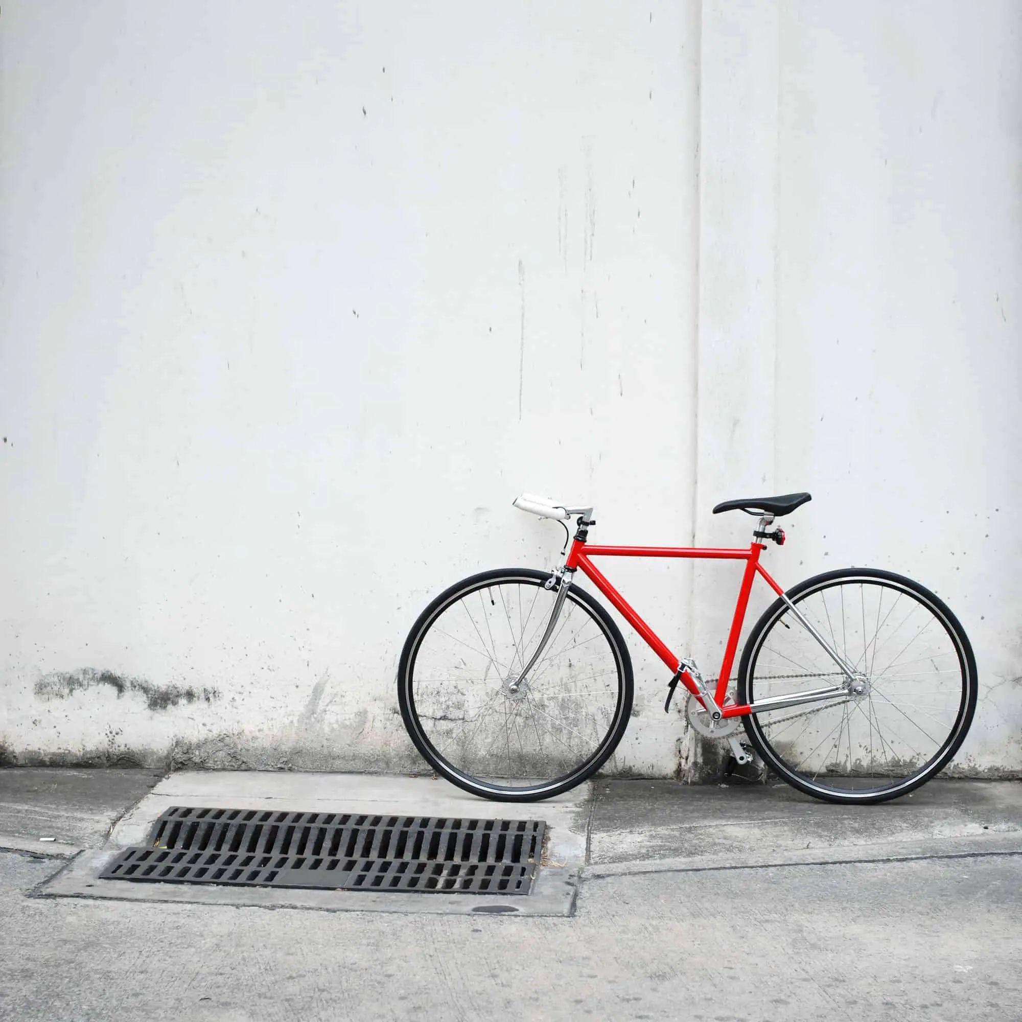 Modern bicycle with a bright red frame leaning on white wall