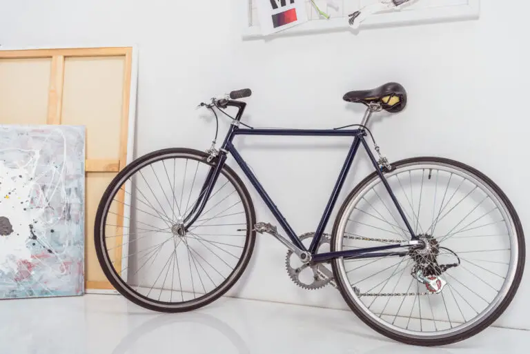 Dark Blue colored road bike set on a while wall with a painting on the side