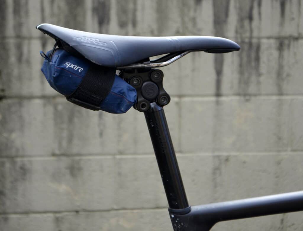A seat post with a small blue bag under the saddle